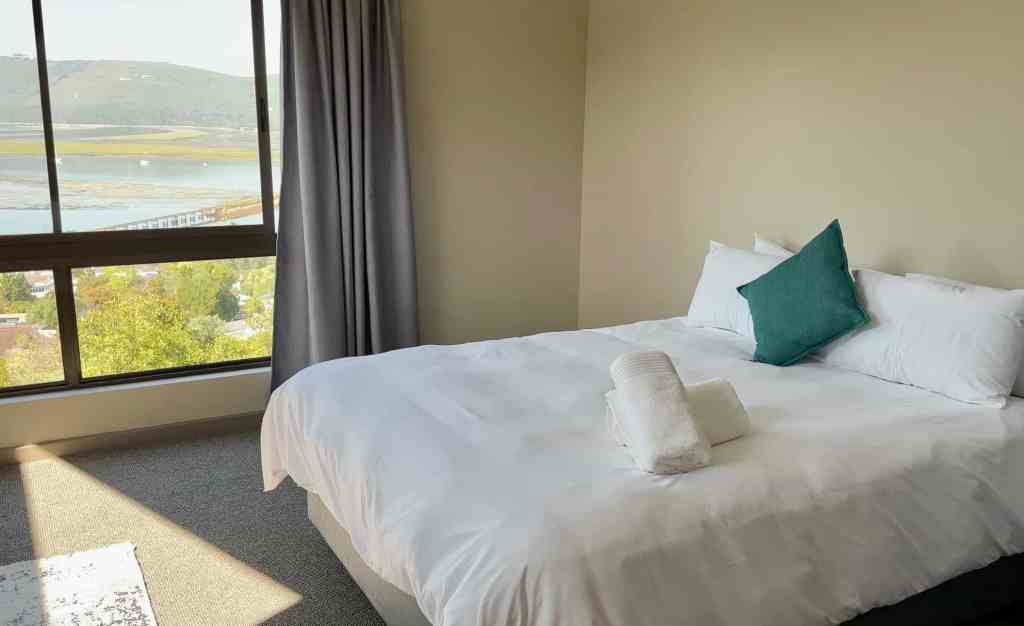 Luxury bedroom with a large window overlooking a scenic lake in South Africa.