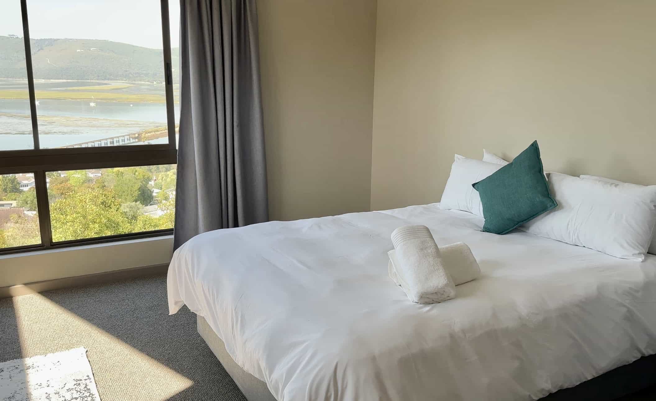 Luxury bedroom with a large window overlooking a scenic lake in South Africa.