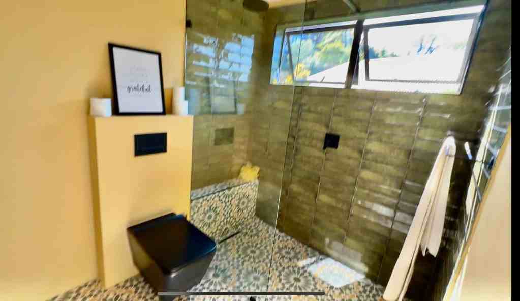 Modern bathroom with patterned tiles, large window, and relaxing decor in South Africa.